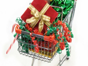 Christmas packages, ornaments candy cane and a bow in a miniature shopping cart.